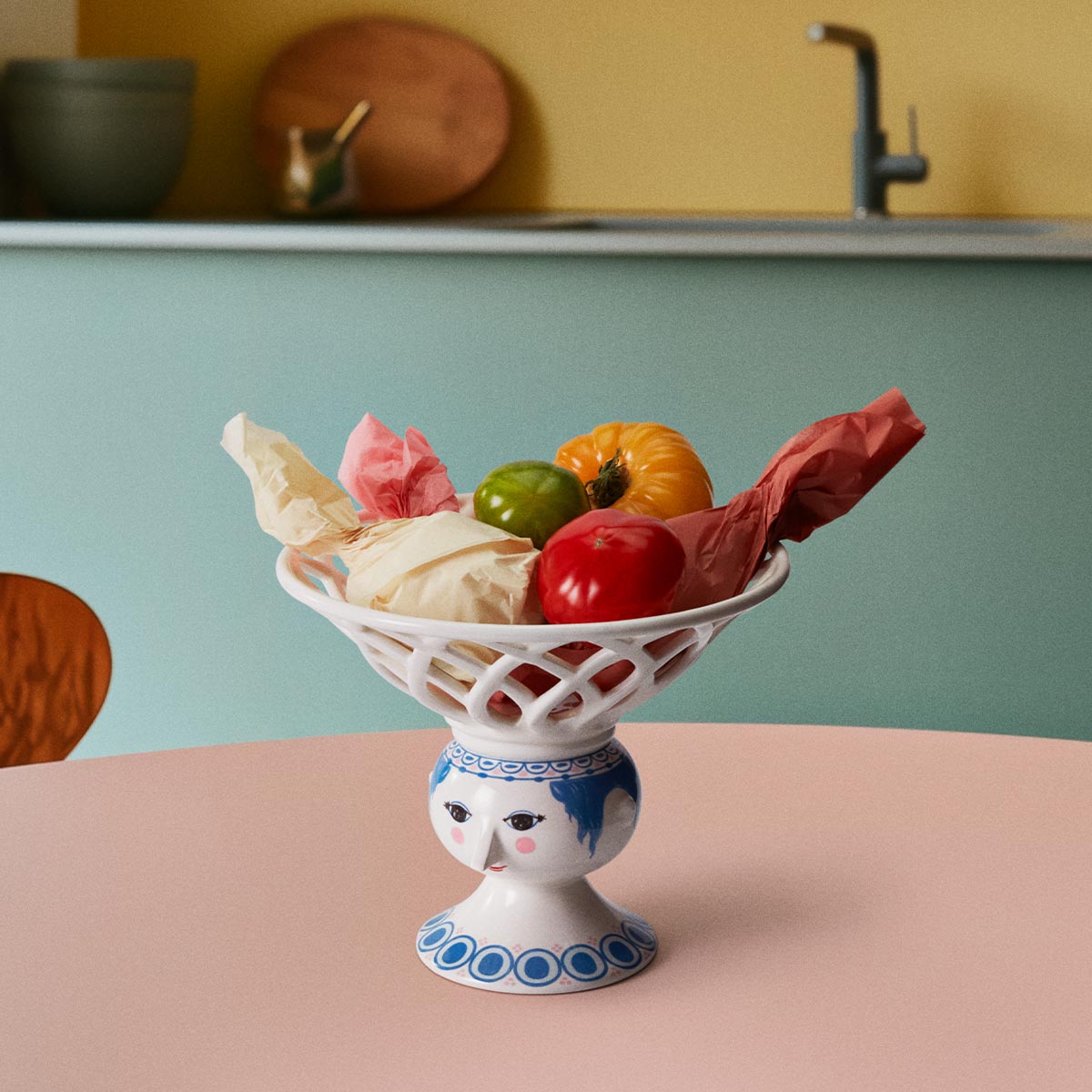Bjorn Wiinblad Dora blue fruitbowl with assorted fruits inside on a pink table