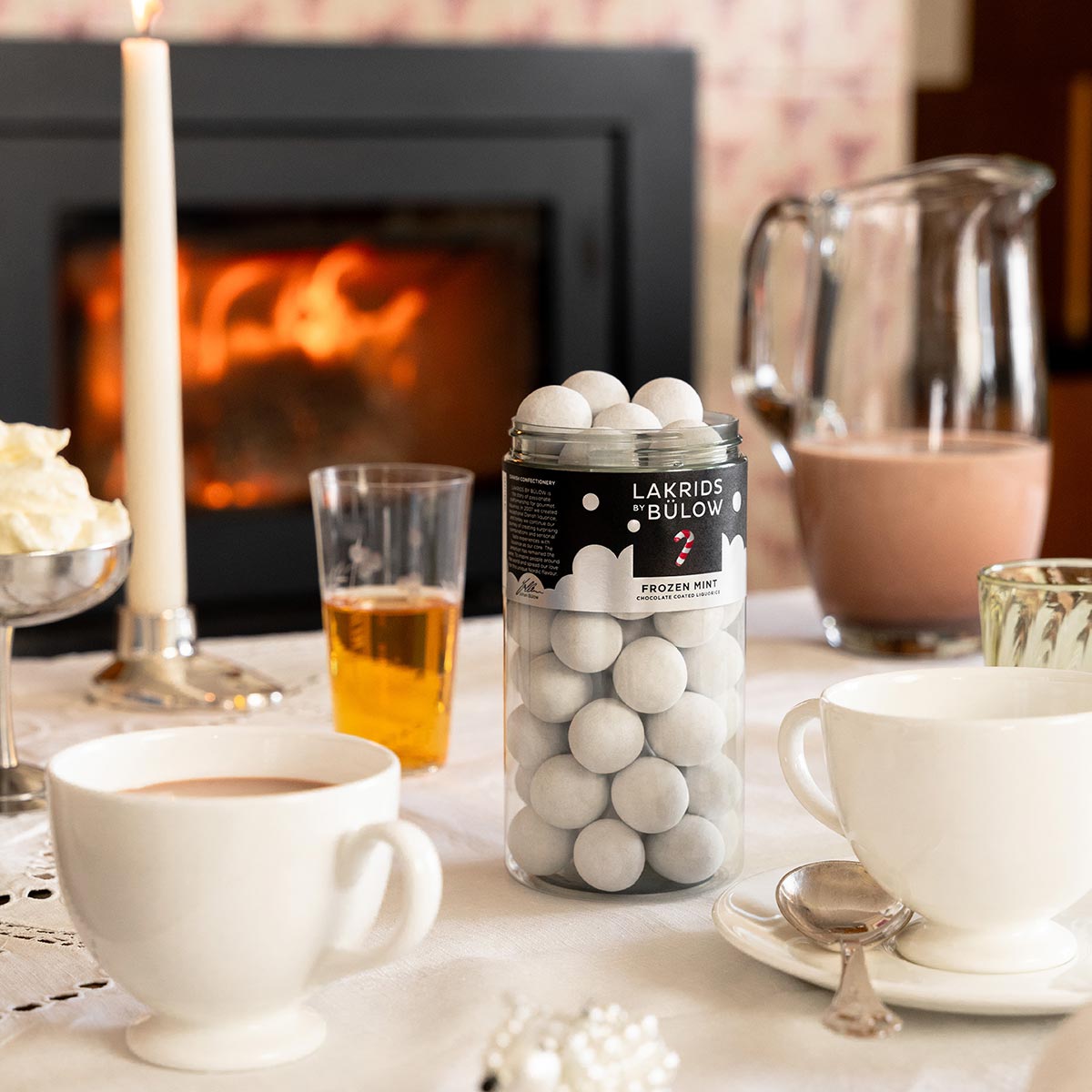Table setting with Lakrids Bulow Frozen Mint liquorice, cups of tea, and a fireplace in the background.