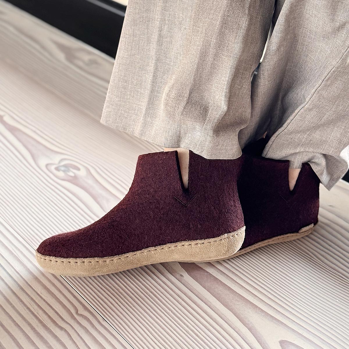A woman wears a pair of glerups boots with leather soles in beet