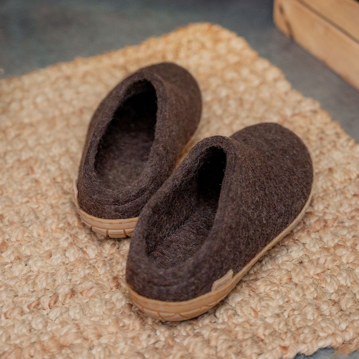Brown rubber soled Glerups mules sit on a raffia doormat