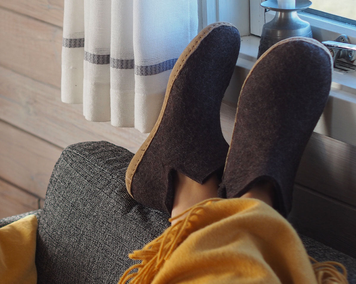 A woman wears a pair of felted Glerups boots in brown with natural leather soles