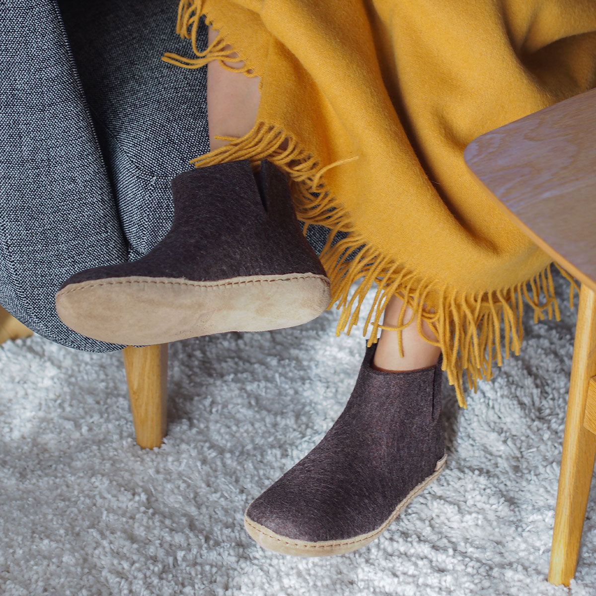 A woman wears a pair of Glerups boots with leather soles in brown
