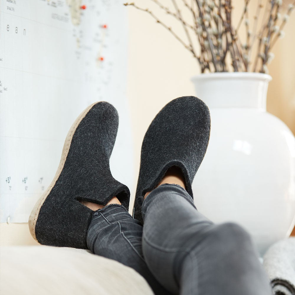 Woman wears a pair of charcoal Glerups boots with leather soles