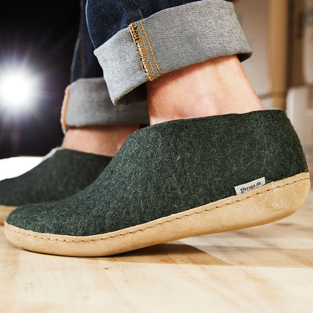A man wears a pair of felted Glerups shoes with leather soled in Forest