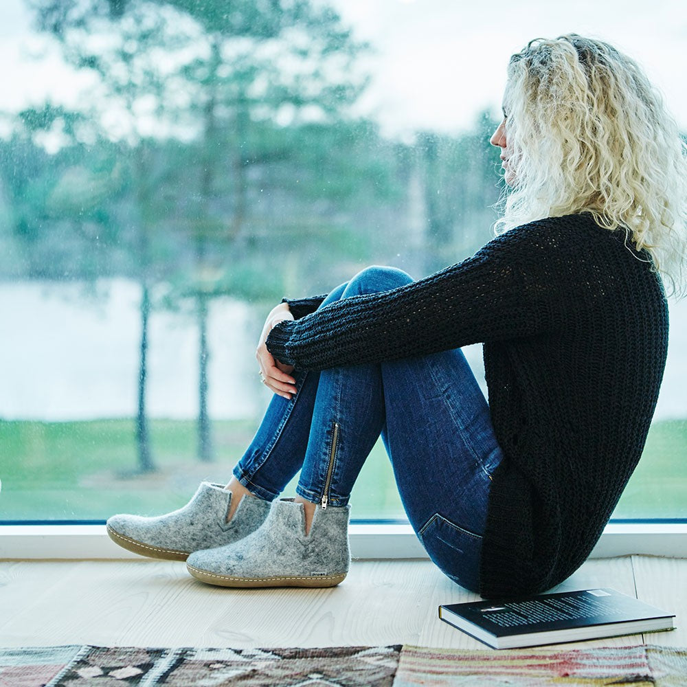 A woman wears a pair of Glerups ankle boots with leather soles in grey