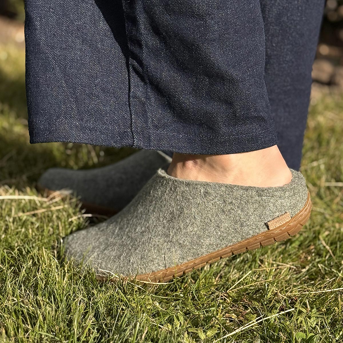Woman wears a pair of Glerups mules with rubber soles in moss outside