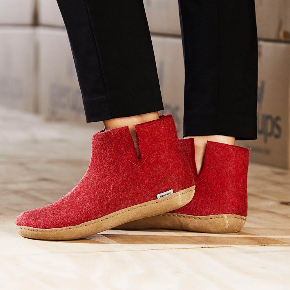 A woman wears Glerups ankle boots with natural leather sole in red