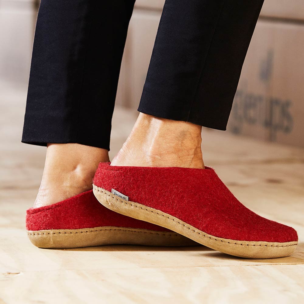A woman wears a pair of red leather soled Glerups in the mule style
