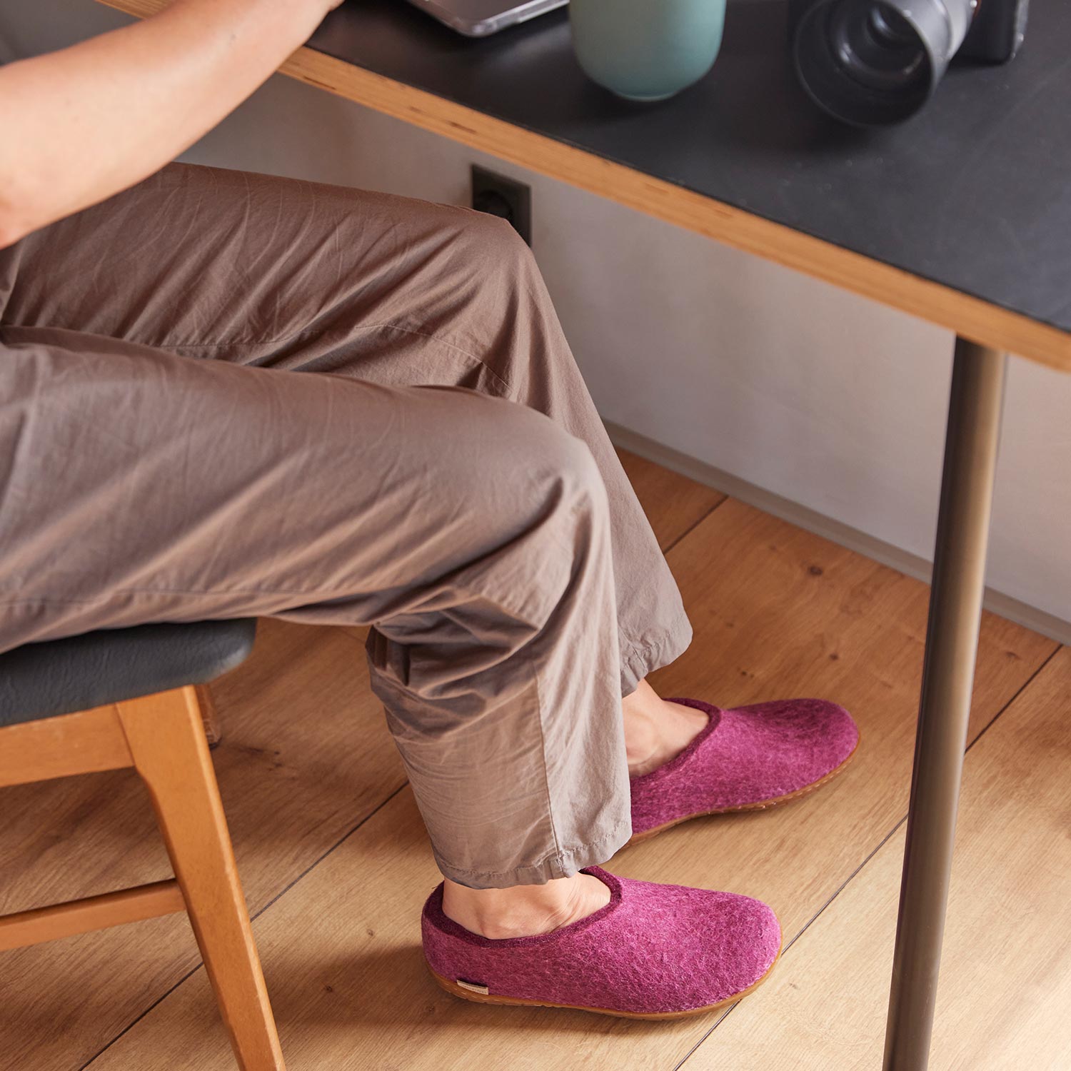 A woman wears a pair of Glerups slippers. Cranberr colour with leather soles in a shoe style