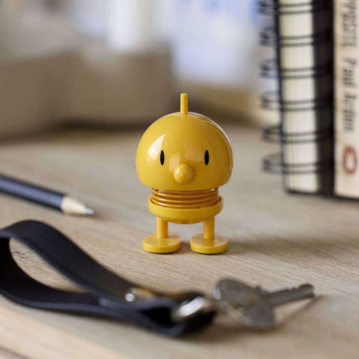 Hoptimist mini yellow bumble on a desk with books and keys