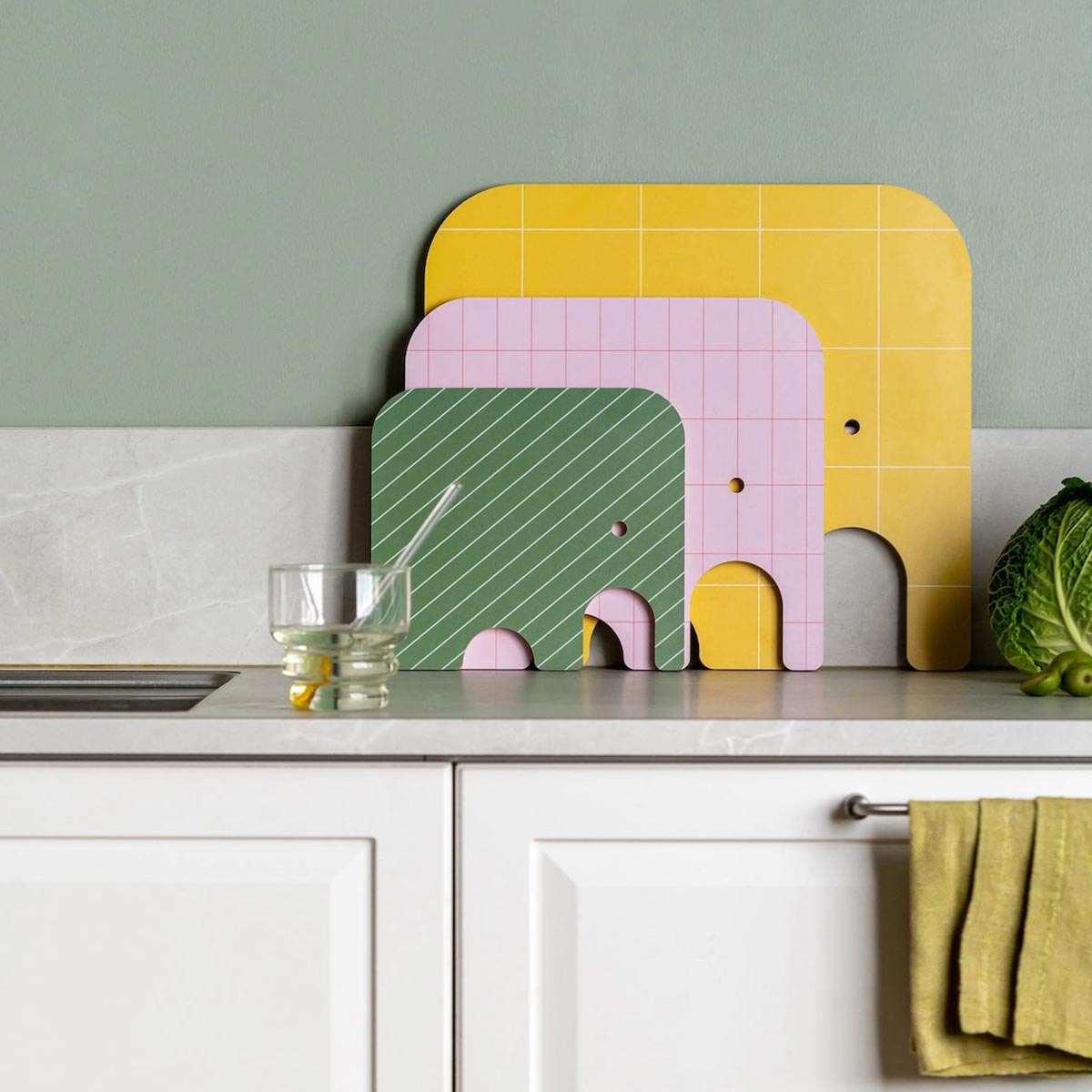 Colorful elephant-shaped cutting boards on a kitchen counter with a green wall background.