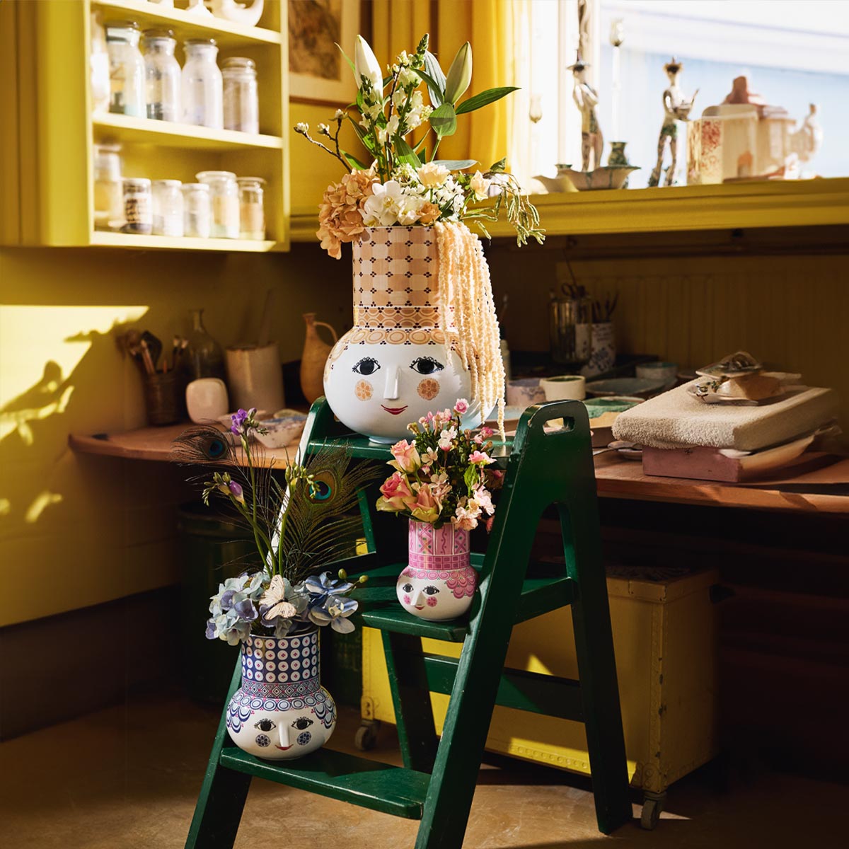 Bjorn Wiinblad Olga vases on a green stepladder with plants and feathers inside