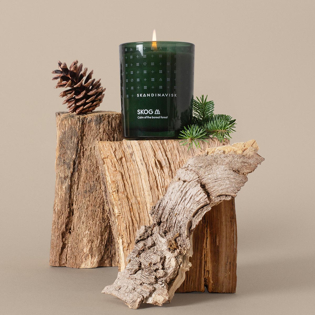 Skog Skandinavisk candle with decorative elements on a wooden surface against a beige background