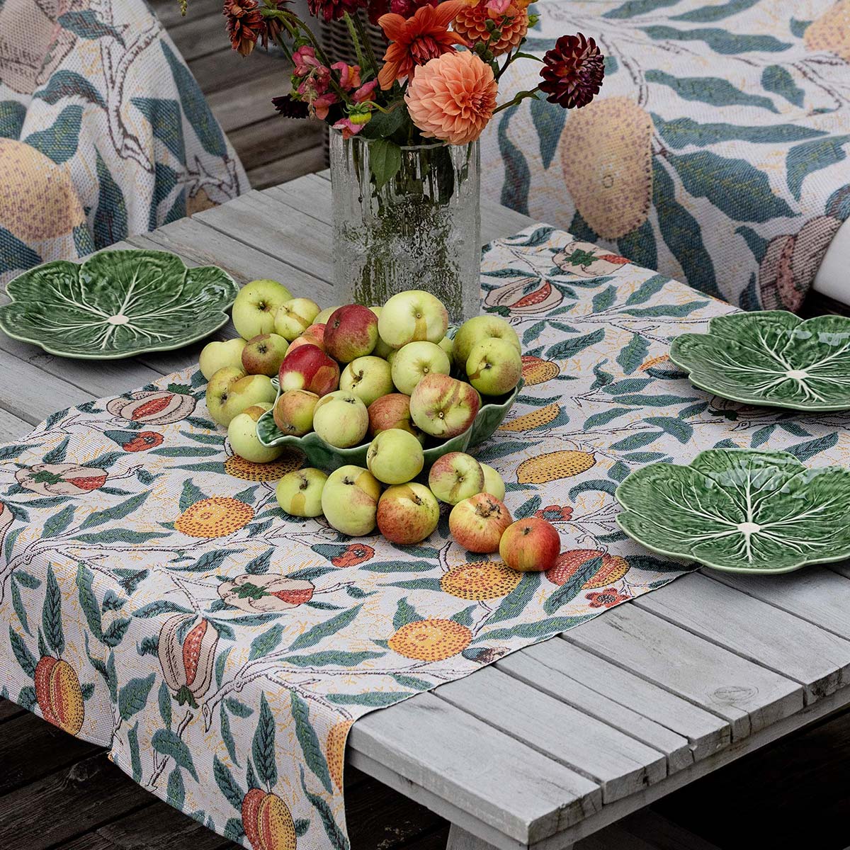Ekelund 'Fruit' William Morris table runner on an outdoors table with green plates and apples