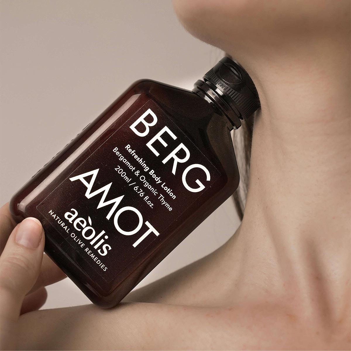Bottle of Bergamot aeolis body lotion held up to a womans neck