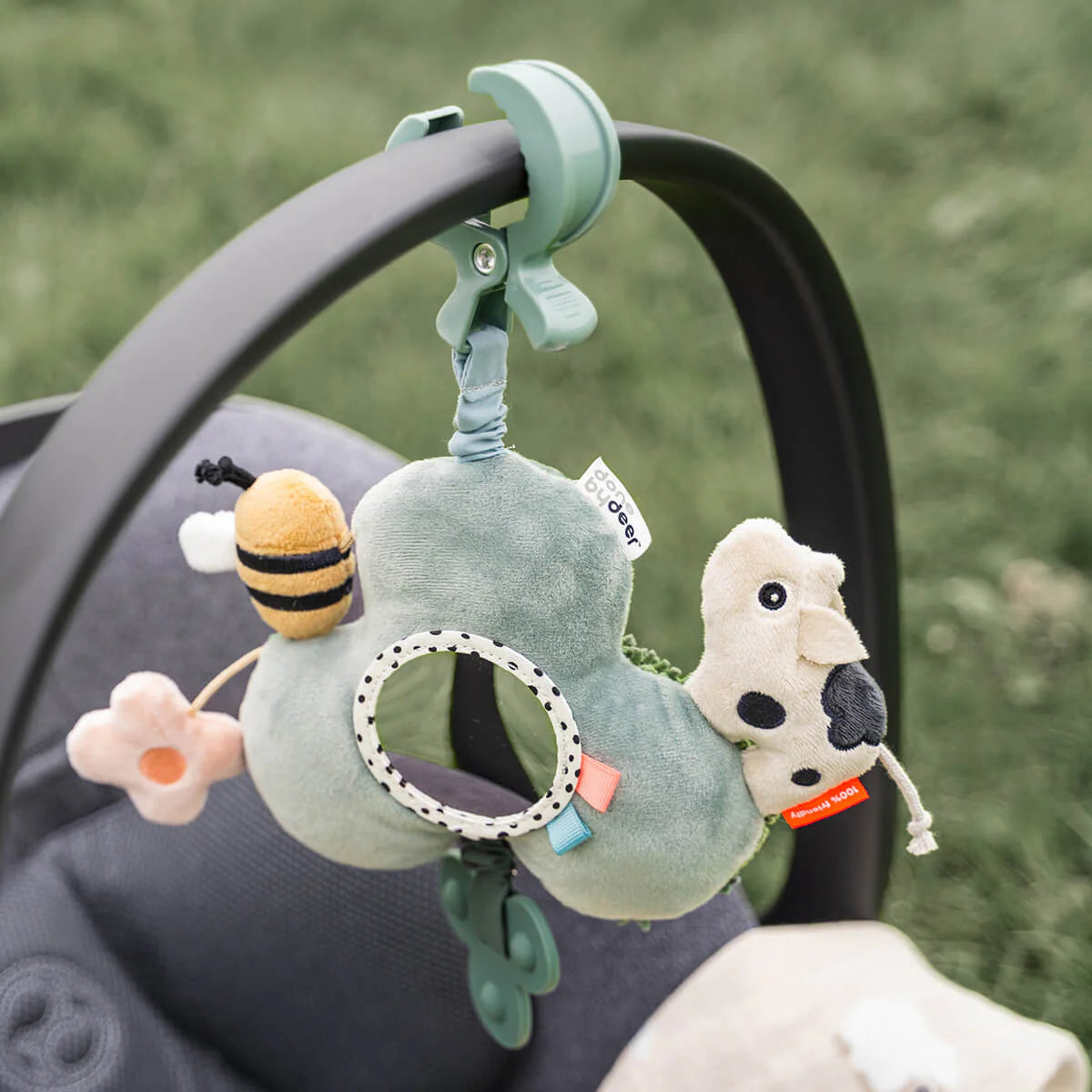 Pushchair on grass with Done by Deer Activity Mirror hanging from the handle.