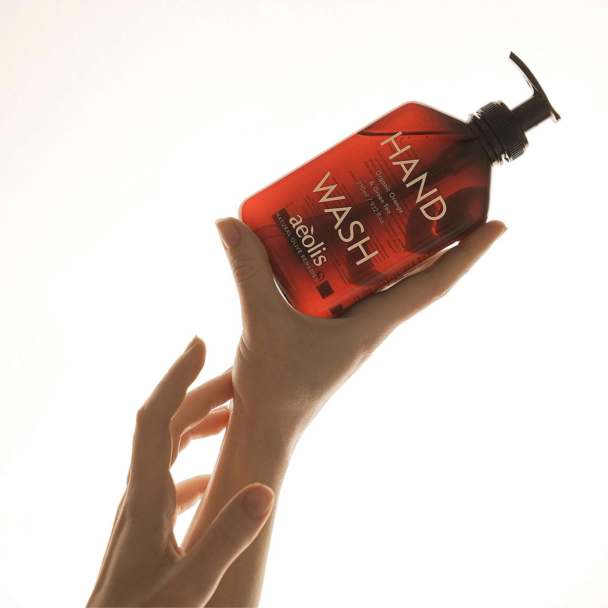 Hand holding a bottle of aeolis hand wash with a white background