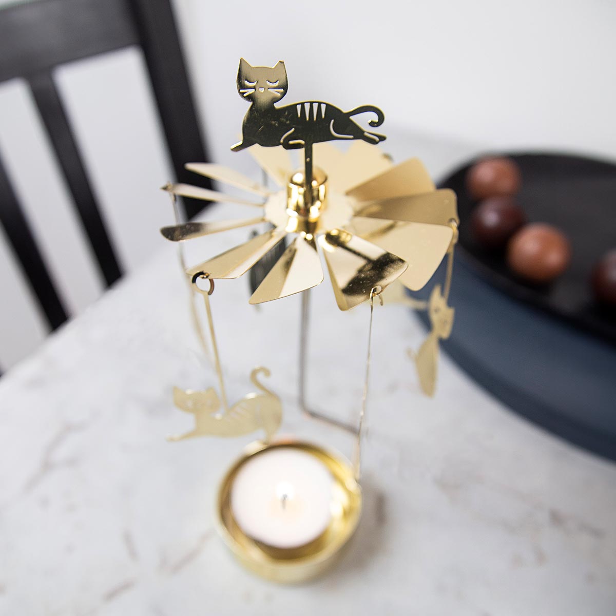 Pluto Design gold metal cat-shaped candle holder with a lit candle.