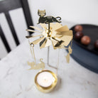 Pluto Design gold metal cat-shaped candle holder with a lit candle.