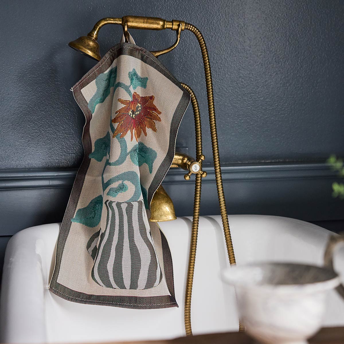 Ekelund 'Amanda' hand towel hooked onto a brass shower and bath unit in a contemporary room