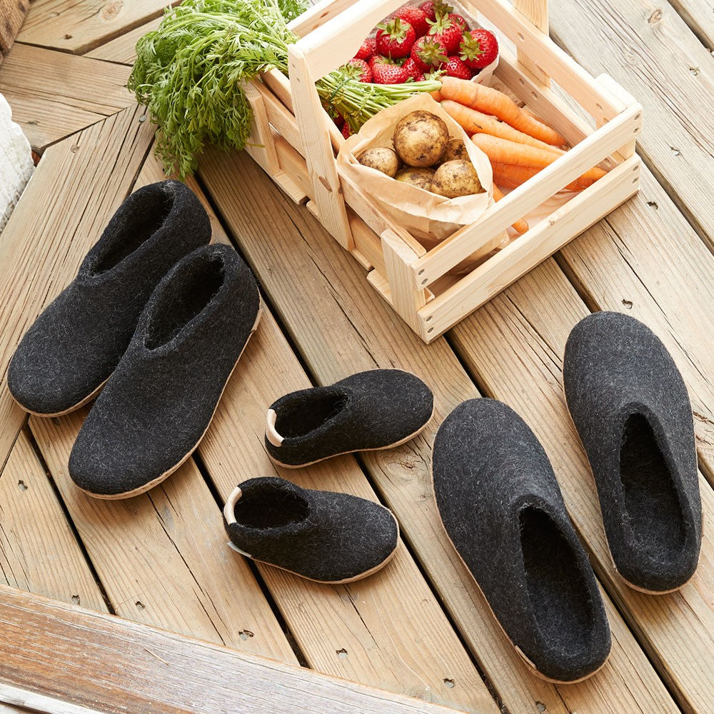 Three pairs of Black soft soled Glerups sit on a decking. Including a pair of Black leather soled shoes