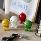 Hoptimist Mini bumble Yellow, White, Red and Green together on a table with books and keyring