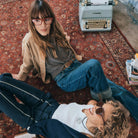 Two people wearing Izipizi glasses sitting on a patterned rug with a typewriter in the background
