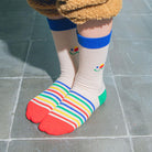 Close -up of Eat My Socks Jolly Bear rainbow-striped socks  on a child's feet.