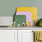Colorful elephant-shaped cutting boards on a kitchen counter with a green wall background.