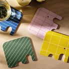 Four elephant-shaped Muurla coasters in different colours on a wooden surface.