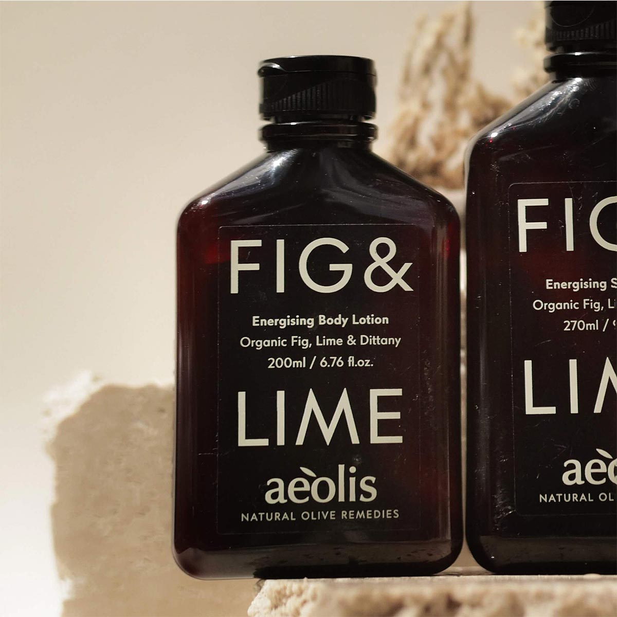Two bottles of Fig & Lime body lotion by aeolis on a textured beige background