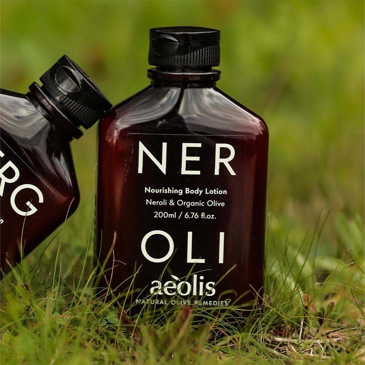 Two bottles of aeolis Neroli Nourishing Body Lotion on grass