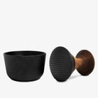 Crushgrind pestle on it's side showing a textured bottom and metal mortar on white background