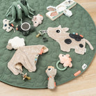 Green mat on a wooden floor with Done by Deer products scattered across it including the 'Sheepy' comfort blanket with a pacifier attached.