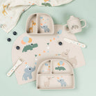 A collection of Done by Deer tableware in the colour 'sand' scattered on a light coloured table with blueberries and a muslin cloth.
