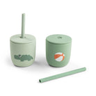 Two green silicone straw cups by Done by Deer set against a white background with one straw lying on its side.