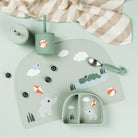 A collection of Done by Deer tableware in mint green scattered on a light coloured table with blueberries and a muslin cloth.