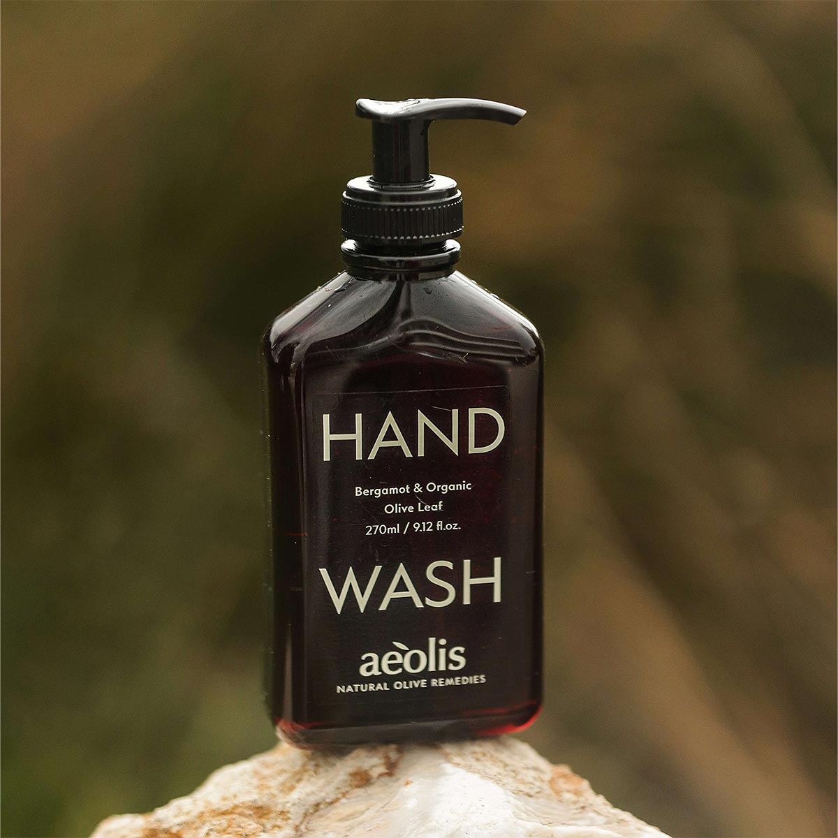 Bottle of aeolis hand wash on a natural rock with a blurred green background