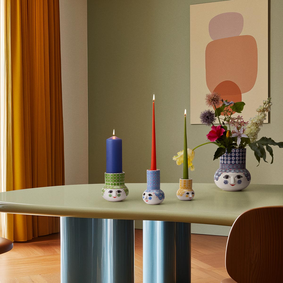 Decorative table setting with Bjorn Wiinblad colourful candle holders and a vase on a light green table.