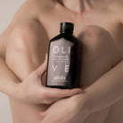 Person holding a bottle of 'aeolis' olive shower gel with a blurred background