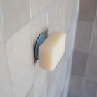 Blue soapi stuck to tiled wall with a bar of soap stuck to it