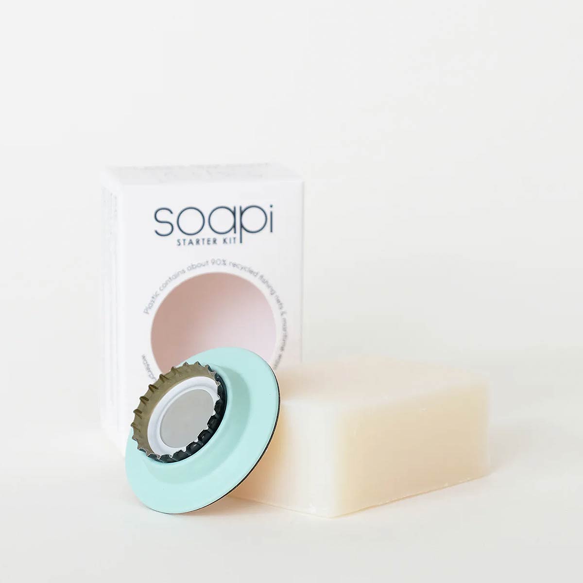 Soapi Starter Kit featuring a pale cream bar of soap, a mint green circular soap dish with a dark metal bottle top, and the white product box in the background.