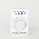 A white rectangular product box for the Soapi Starter Kit, featuring a circular cutout window that reveals a white magnetic soap holder inside. The packaging text highlights recycled fishing net and marine wax materials, and lists the product as a magnetic soap holder plus soap and recycled bottle cap.